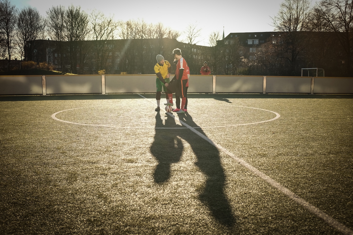 Trainer leitet zwei Spieler am Anstoßkreis an und erklärt Fußstellungen
