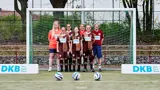 Das Frauen-Team steht vor einem Tor, DKB-Banden an den Seiten. 
