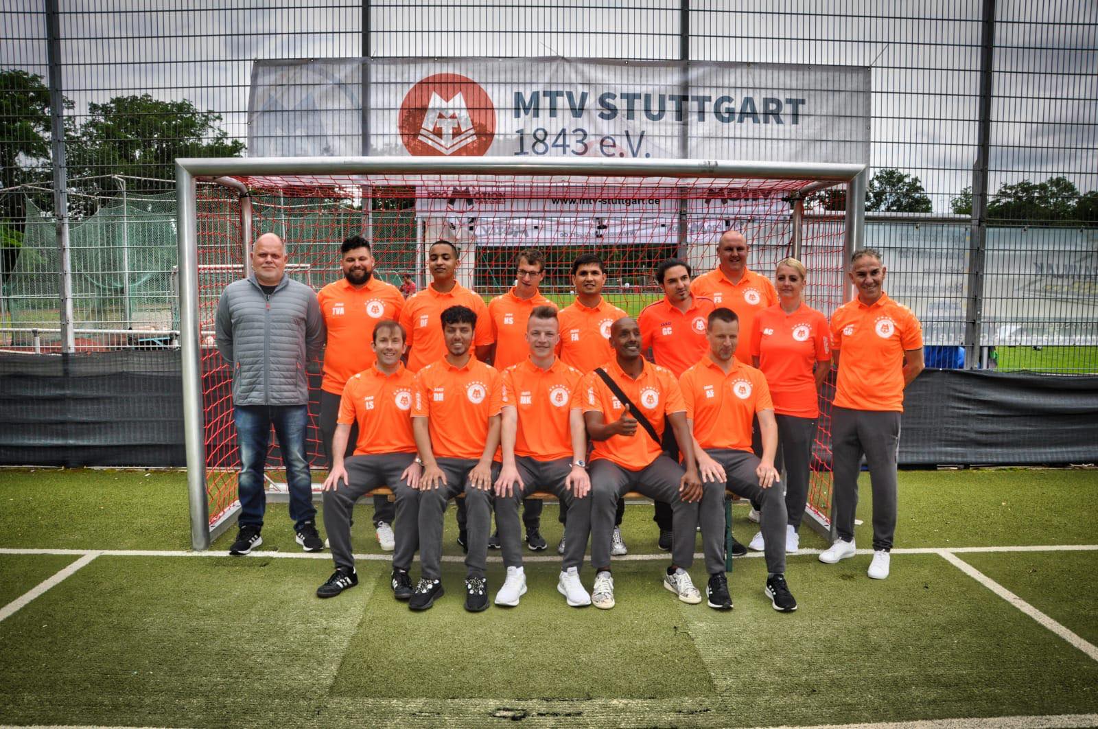 Das Team steht in zwei Reihen vor einem Tor