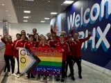 Grupenfoto im Flughafen Birmingham. Das Team hält eine Pride-Fahne mit der goldenen Aufschrift "go germany"